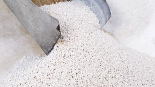 small white granules coming out of a granulator