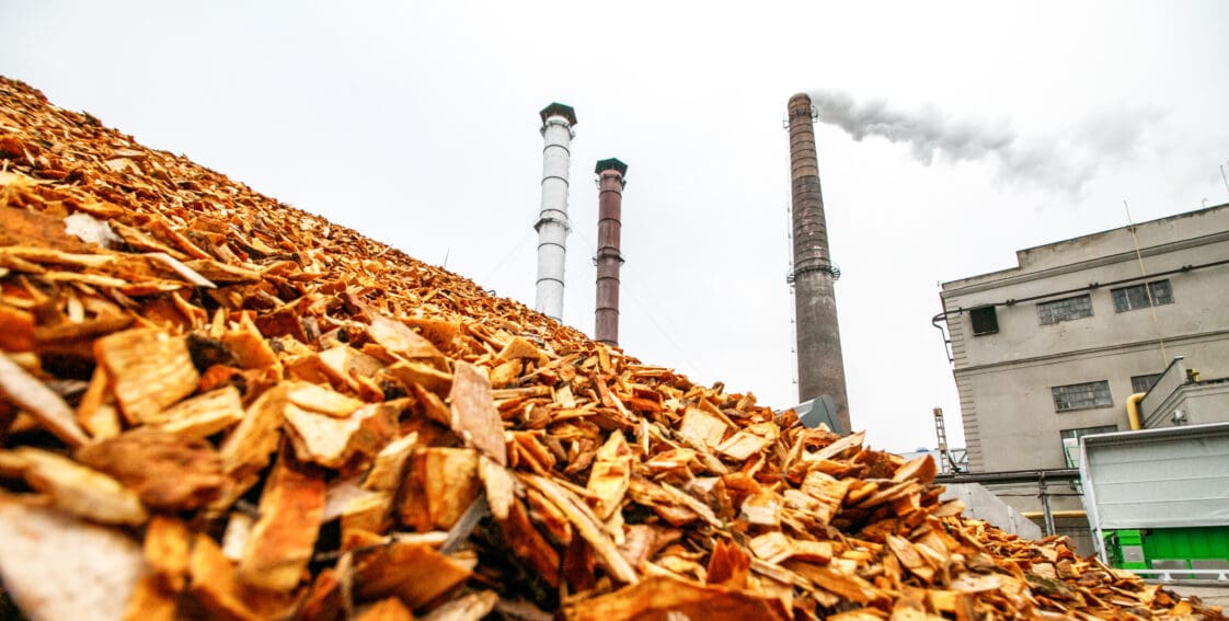 Pile of biomass with energy factory in the background